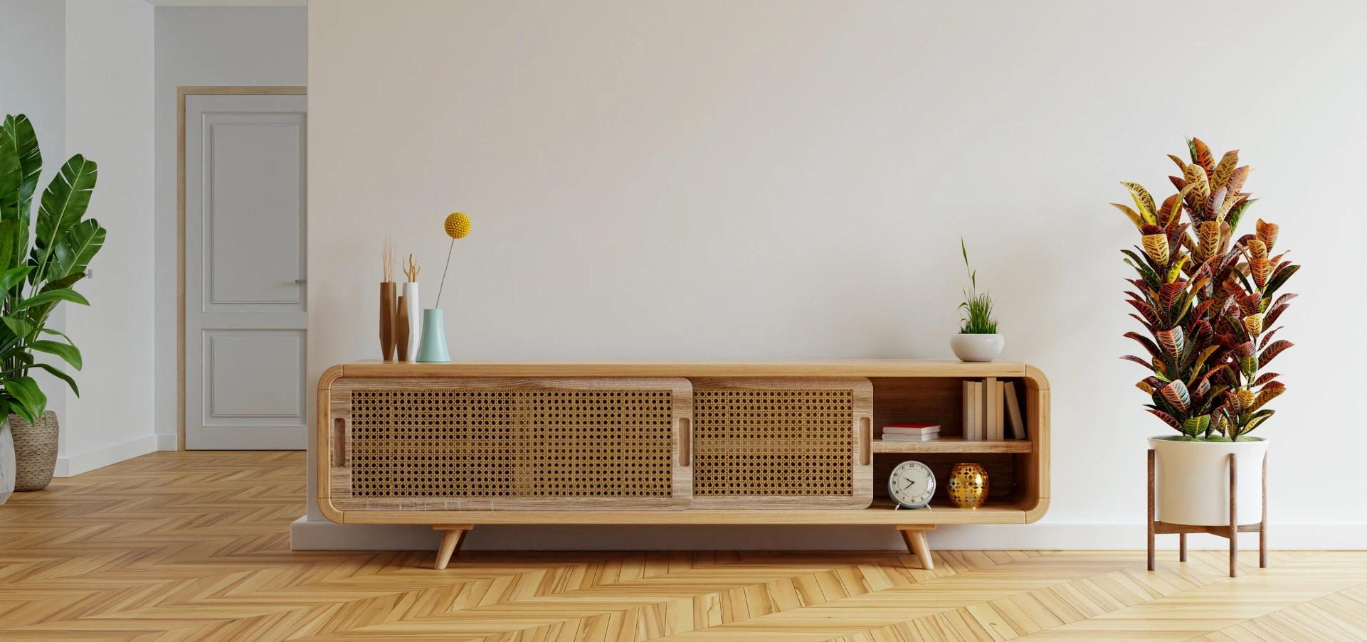 Modern living room with a stylish wooden console featuring rattan cane sliding doors, placed against a neutral wall with indoor plants for decoration.