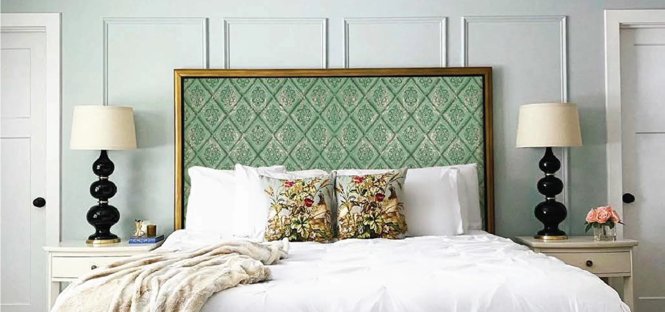 Soft pastel green fabric wall panels used as a headboard in a cozy bedroom with white bedding and elegant decor.