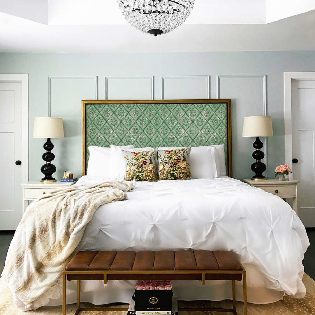 Soft pastel green fabric wall panels used as a headboard in a cozy bedroom with white bedding and elegant decor.