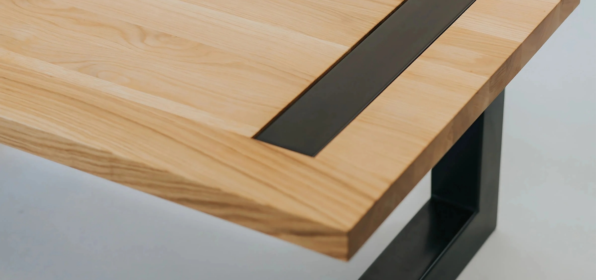 Close-up of a plywood table with a sleek black metal frame, showcasing its smooth finish and modern design