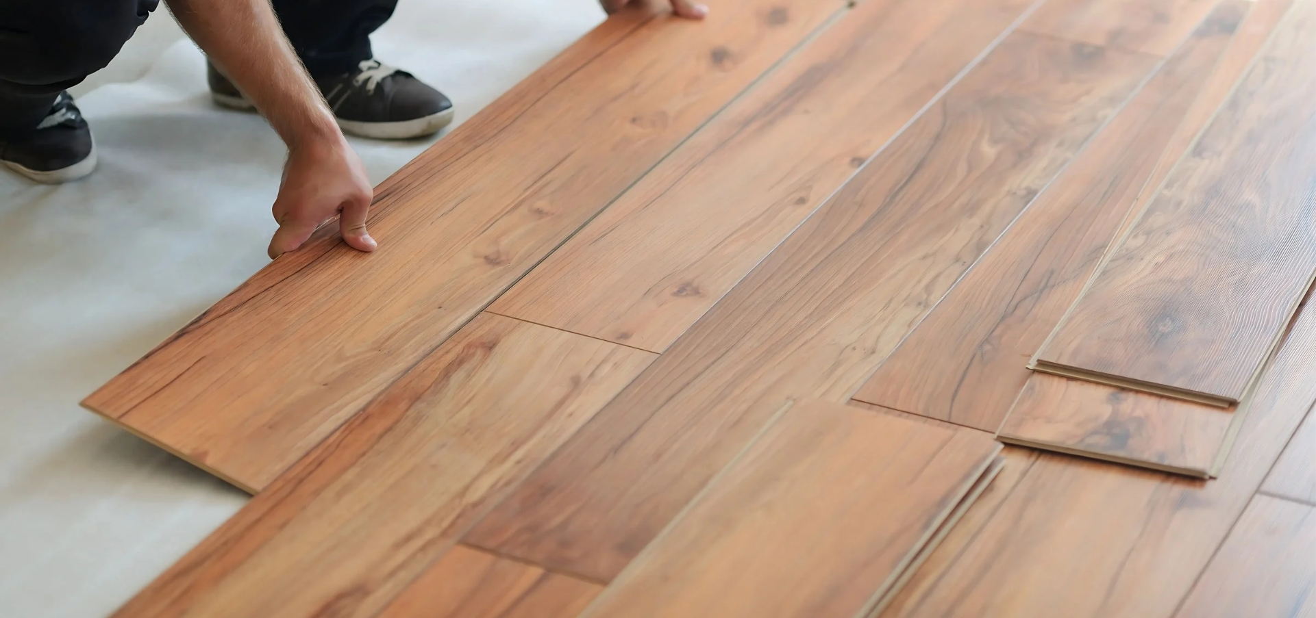 Hands installing wooden plywood flooring panels for interior design purposes