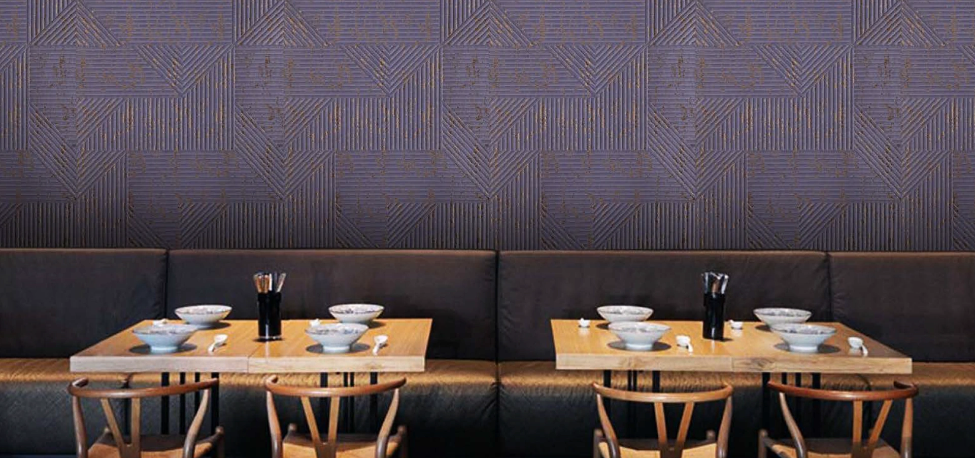 A stylish dining space enhanced by a dark navy fabric wall with a geometric pattern, complemented by wooden furniture and black seating.