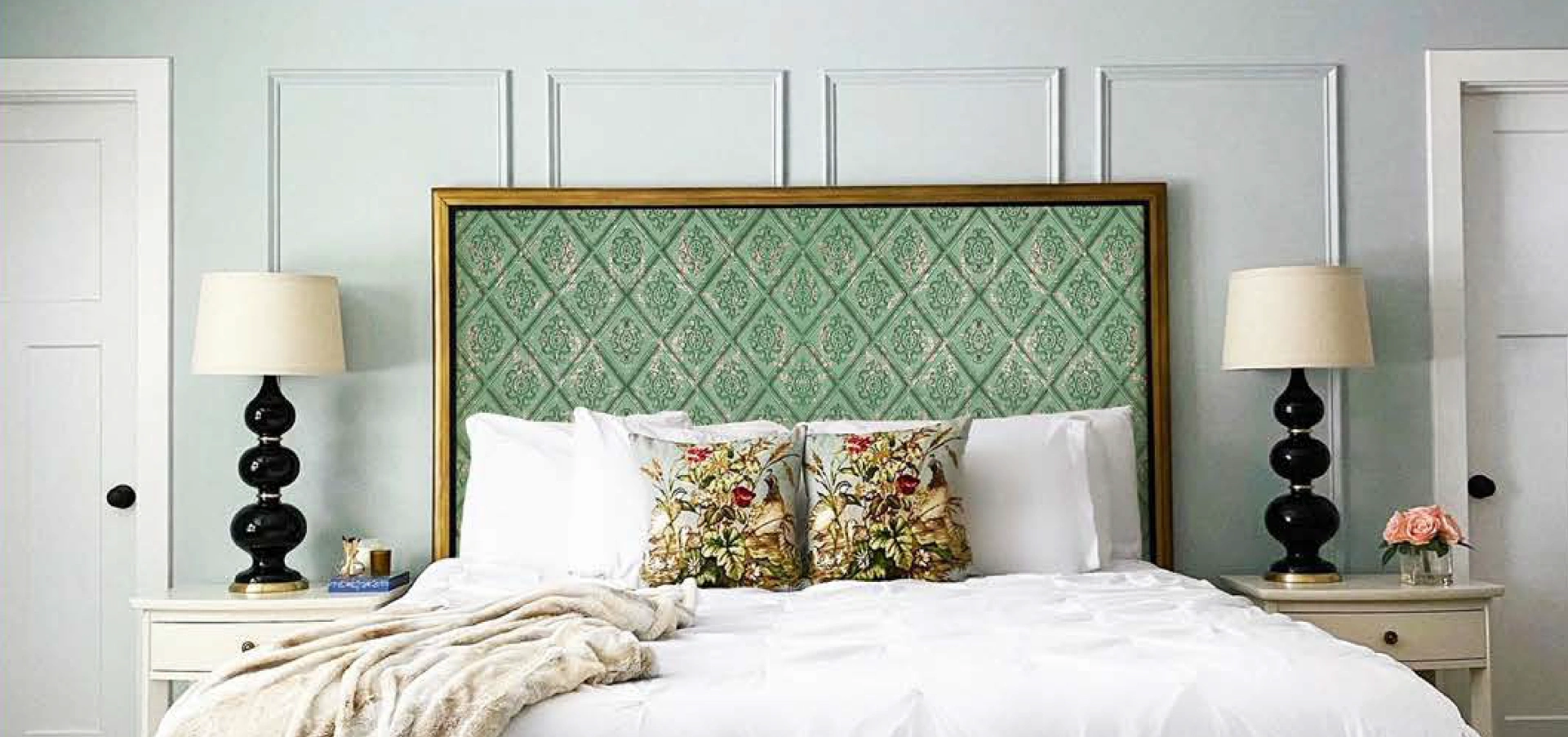 Soft pastel green fabric wall panels used as a headboard in a cozy bedroom with white bedding and elegant decor.